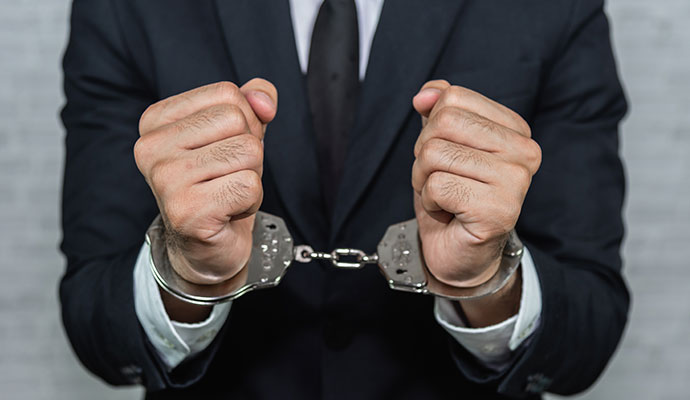 Black suit man with his hands in handcuffs