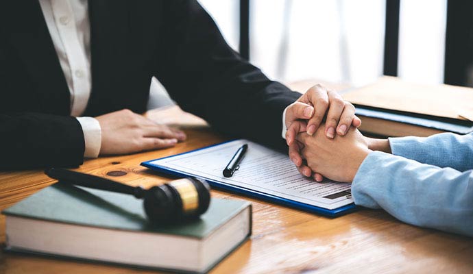 A professional in a black blazer placing a supportive hand over a client's clasped hands