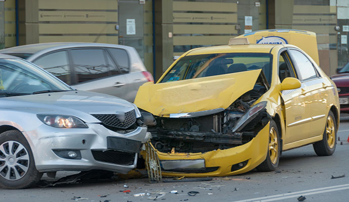 Silver car yellow taxi head on collision