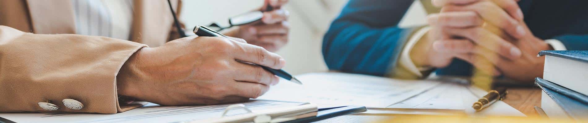 Two professionals in business attire reviewing and signing legal documents