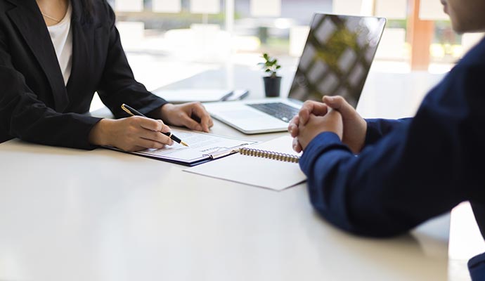 Two professionals in business attire sitting across from each other at a white desk