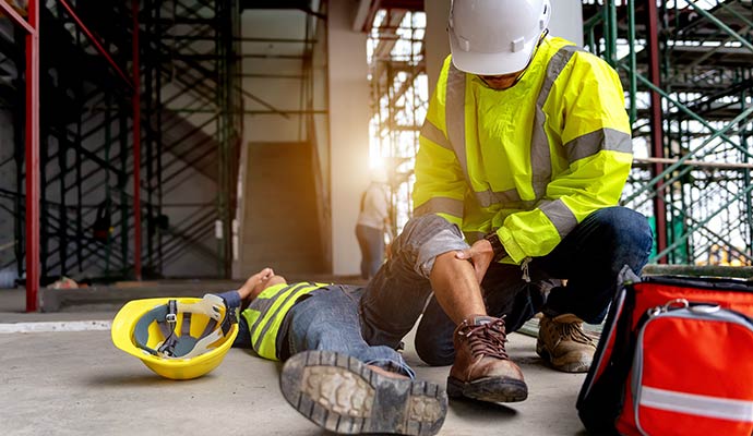 A construction worker kneel down to help an injured worker